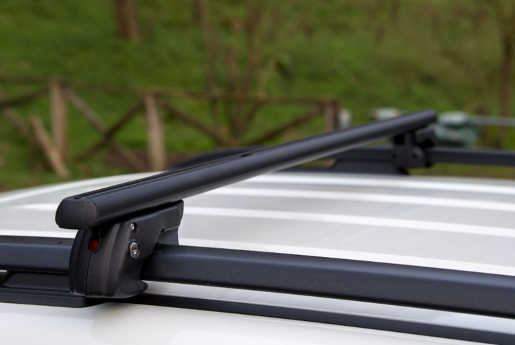 A slim roof bar mounted on a white vehicle