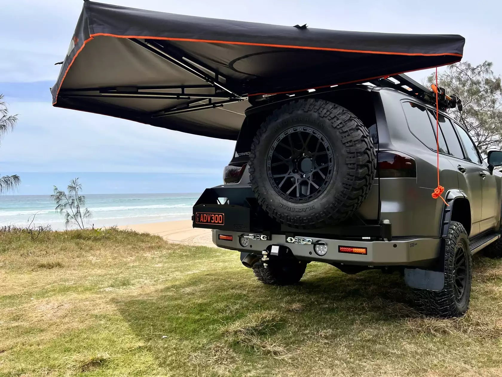 Awning black Campboss side panel unfolded on a 4x4 in front of the sea