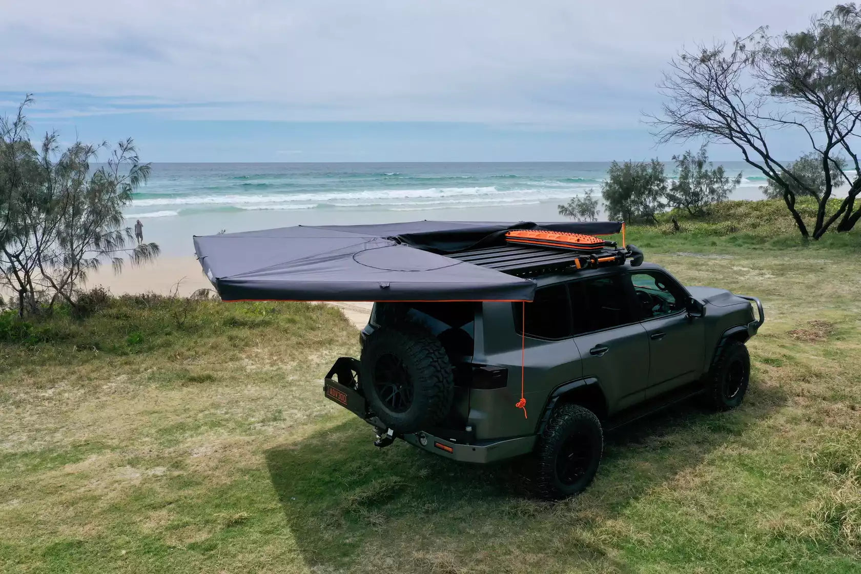 Black and orange circular awning unfolded on the left of a 4x4