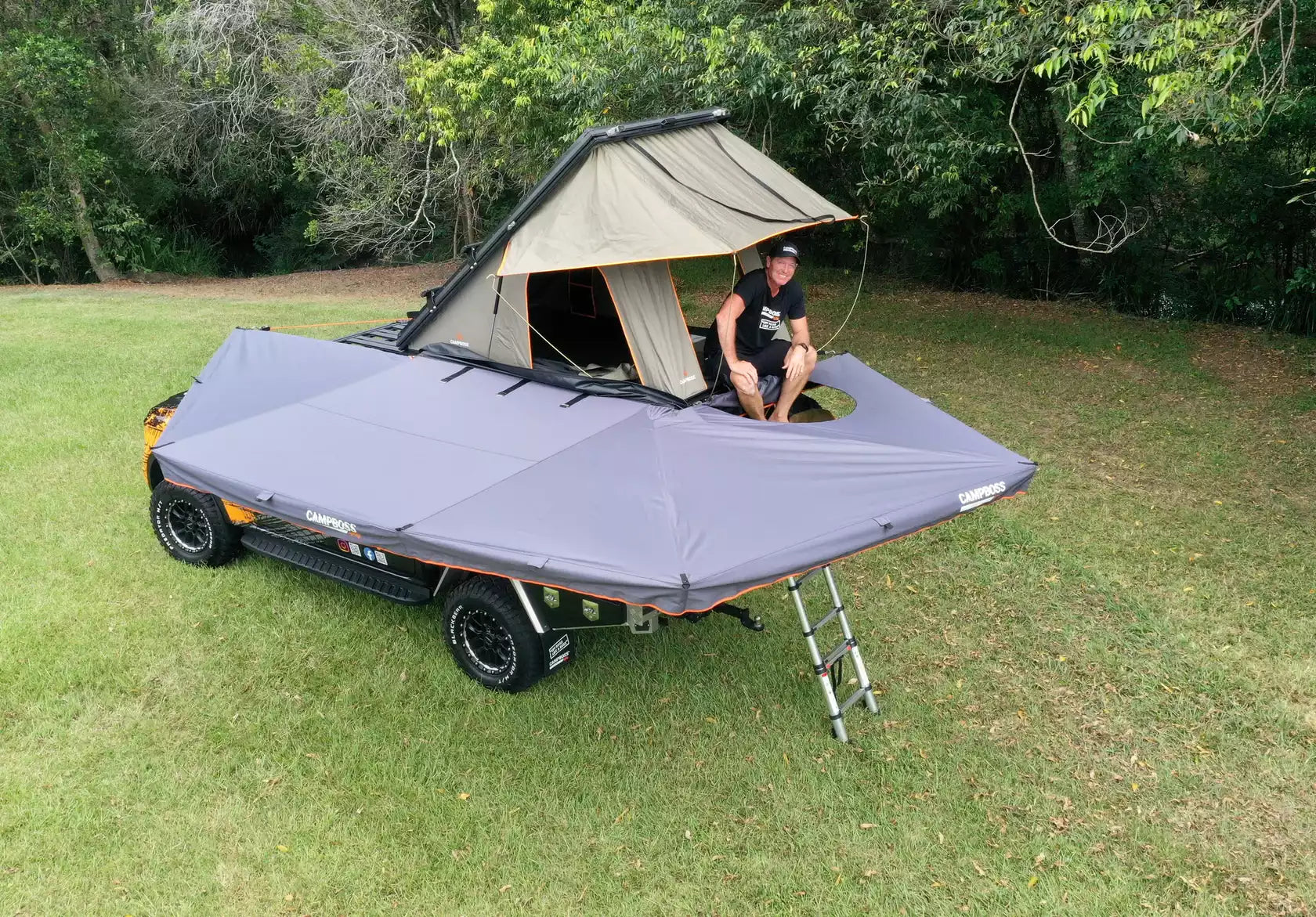 A man set up in his roof tent in his bivouac on the Awning