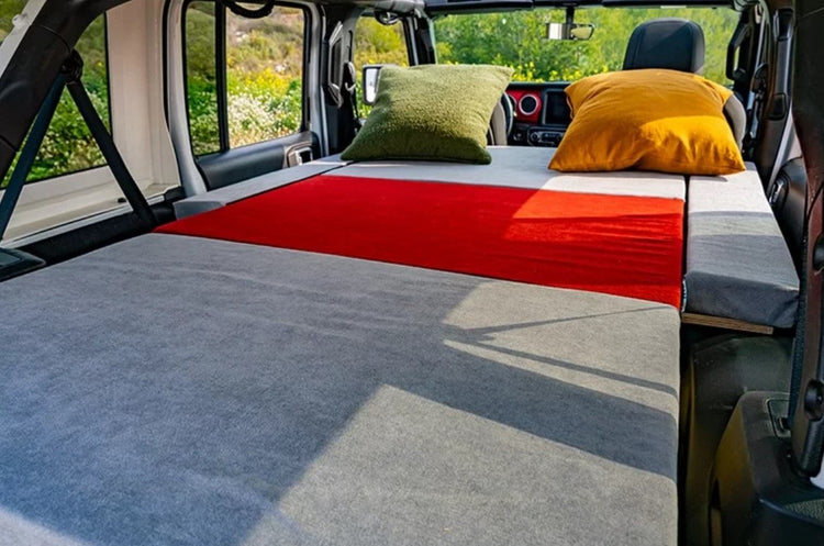 grey and red mattress in a van with 2 pillows