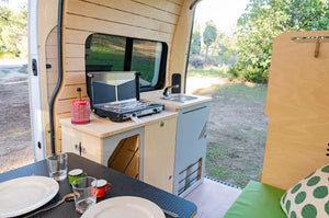 Van furnished with a bed and kitchen area and a side window