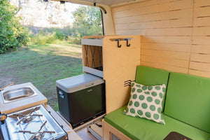 green bench seat in a van with furniture and fridge