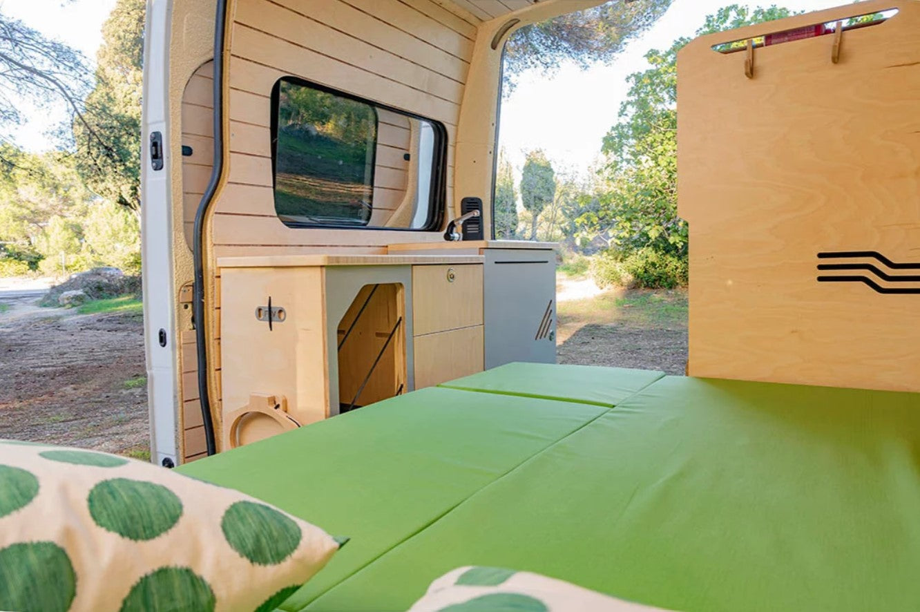 fully unfolded bed with green mattress in a converted van