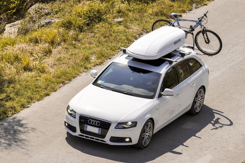 White Audi with white roof box and bike behind
