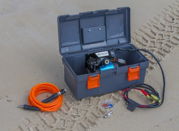 grey case with compressor inside, lying on the sand