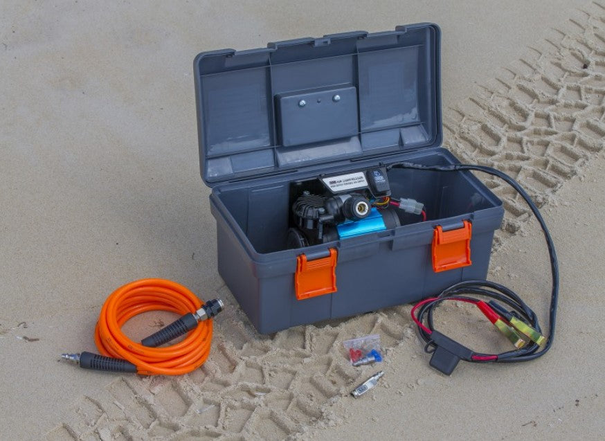 grey case with compressor inside, lying on the sand