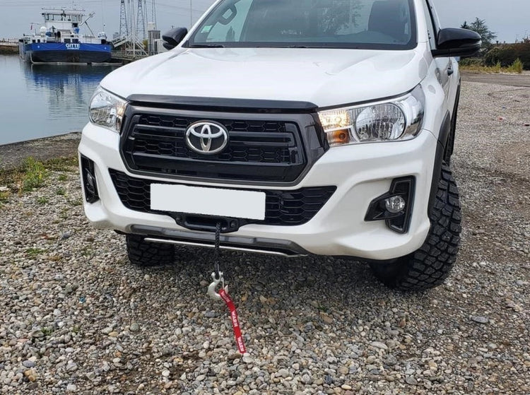 Front white Toyota in front of a boat with a protruding cable