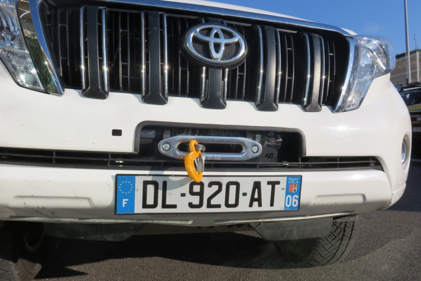 front end of a white toyota vehicle with a protruding tree trunk
