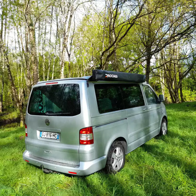 Grey Volkswagen Transporter parked in the grass with a closed and tidy Awning