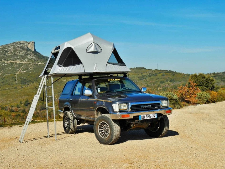 Toyota V8 in front of a hill with a roof tent