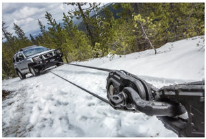 Nissan in the snow pulled by a shackle-mounted winch warn