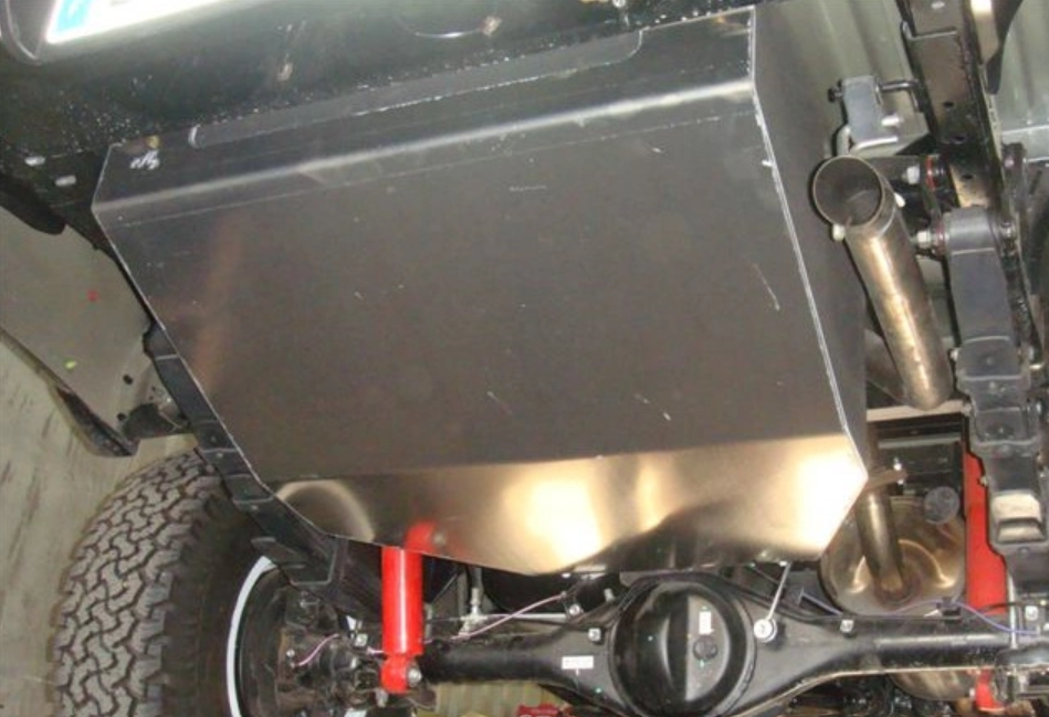 steel tank mounted under a vehicle with red shock absorbers