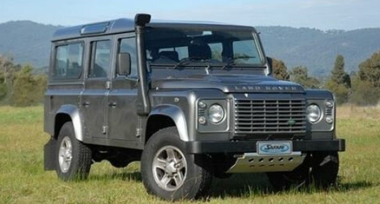 land rover defender 110 green in the grass with a black snorkel