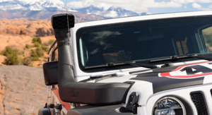 front view of a jeep with a snorkel and a mountain landscape