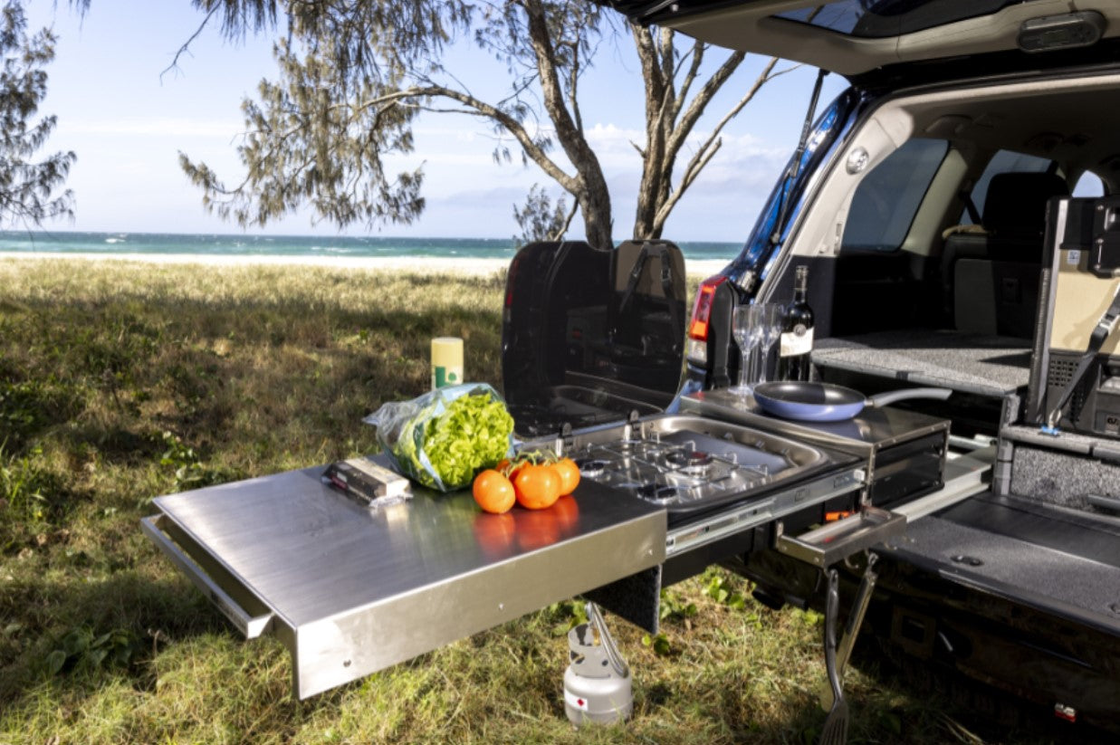 back of a vehicle in front of the sea with an open kitchen