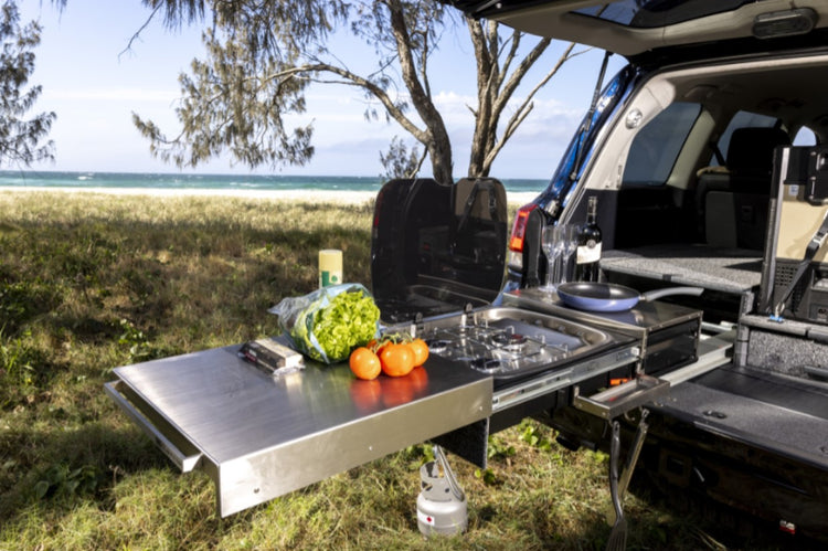 back of a vehicle in front of the sea with an open kitchen