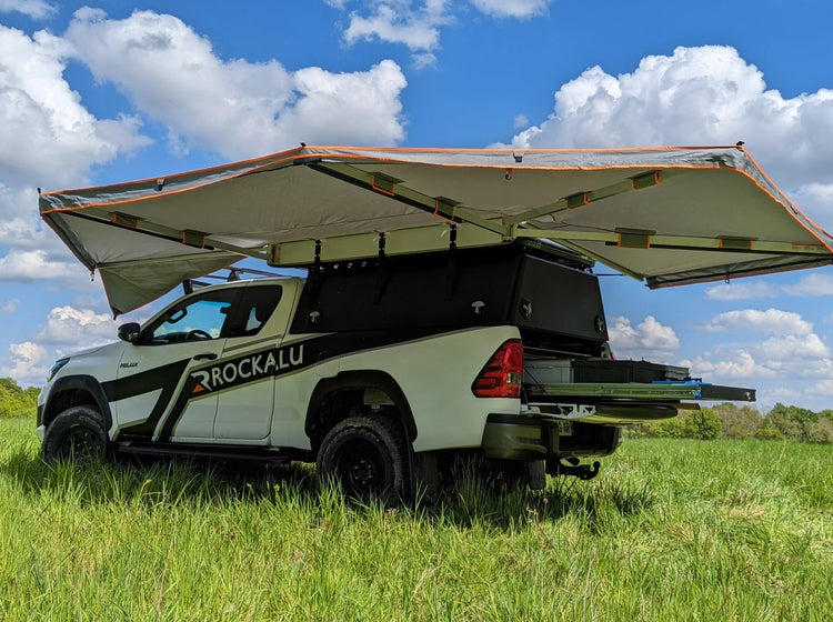 Awning circular Rockalu car carrying open and unfolded in a plain of green grass, on a Toyota 4x4. 